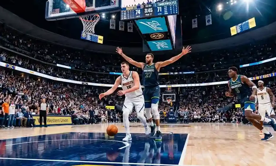 Nikola Jokic making a bounce pass while guarded by Rudy Gobert with Anthony Edwards cutting along the perimeter during a Denver Nuggets vs Minnesota Timberwolves NBA game.
