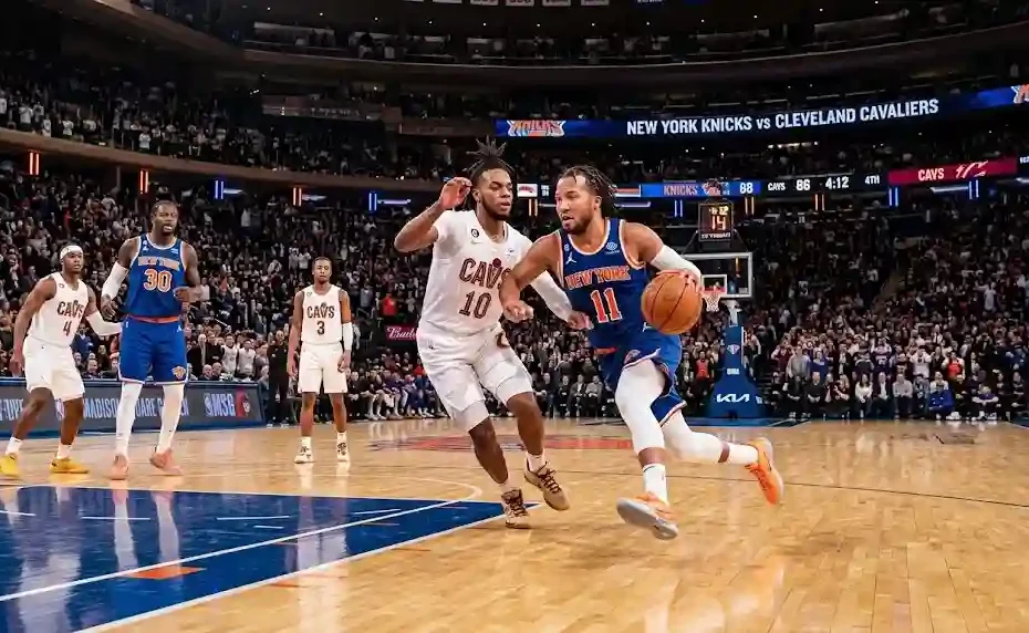 A New York Knicks point guard driving past a Cleveland Cavaliers defender during an intense NBA game inside a packed arena.